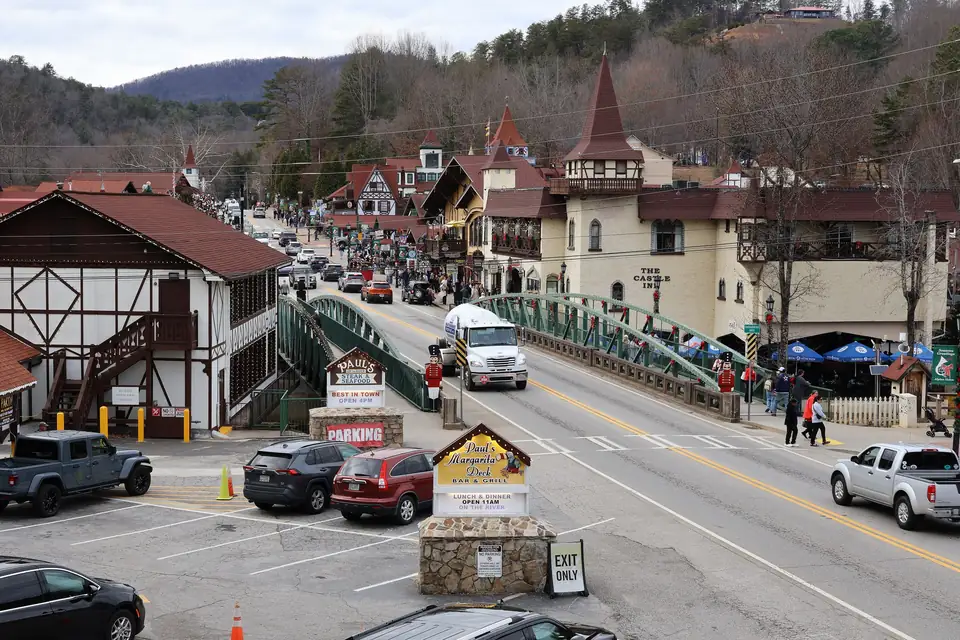 Bavarian-style buildings, a green steel bridge with wreaths, nutcracker figures and crowds on a main street below wooded hills