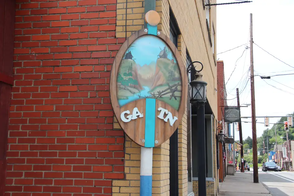 Oval painted sign reading 'GA. TN' split by a blue stripe, mounted on a brick building beside a lantern and sidewalk